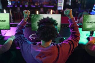 Homem jogando videogame e celebrando vitória, visão traseira do jogador.