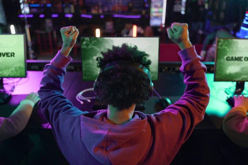 Homem jogando videogame e celebrando vitória, visão traseira do jogador.